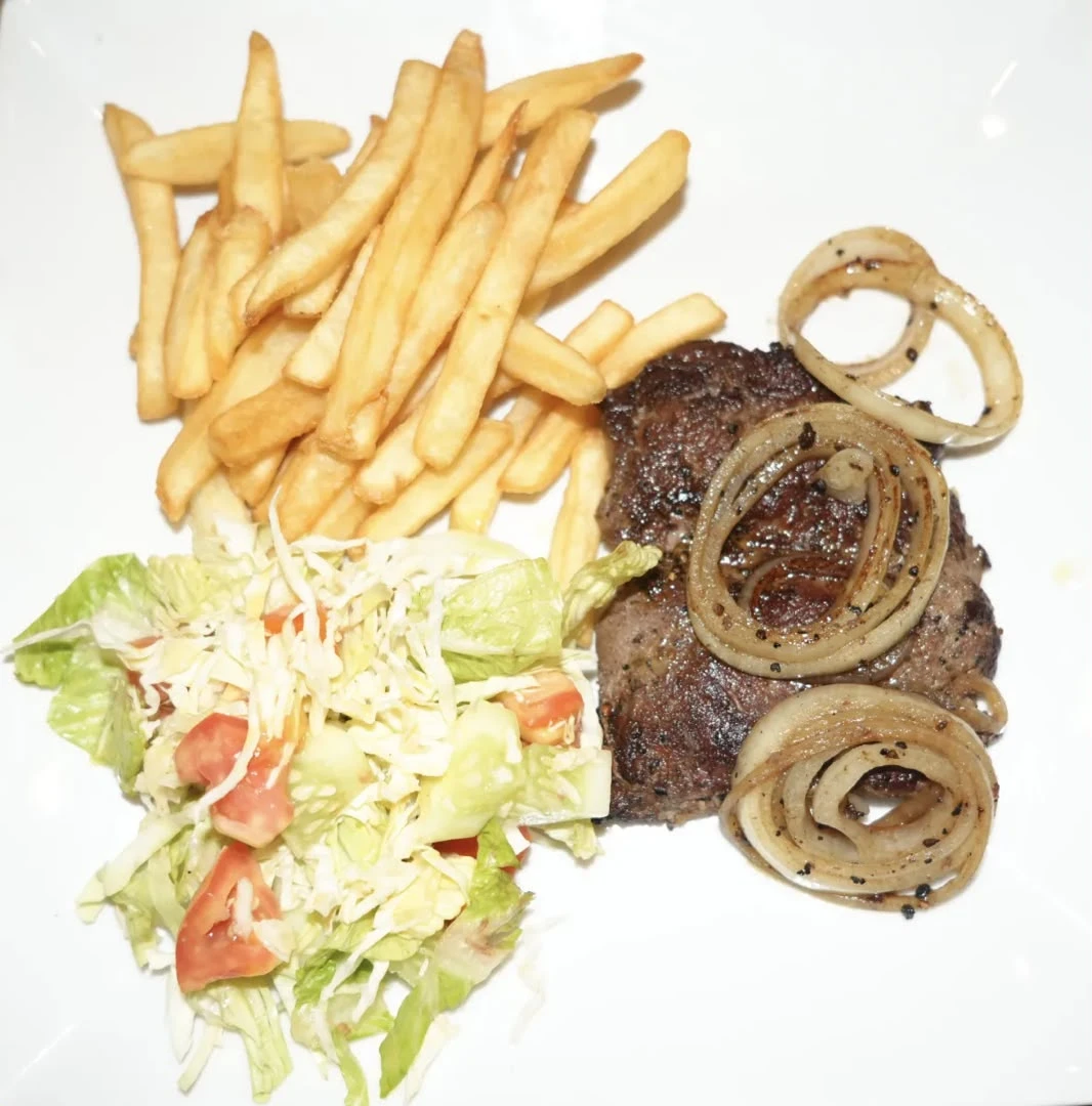 Grilled Fillet Steak Grilled fillet steak topped with onions, served with fried rice or chips, mixed vegetables or salad, and creamy steak sauce